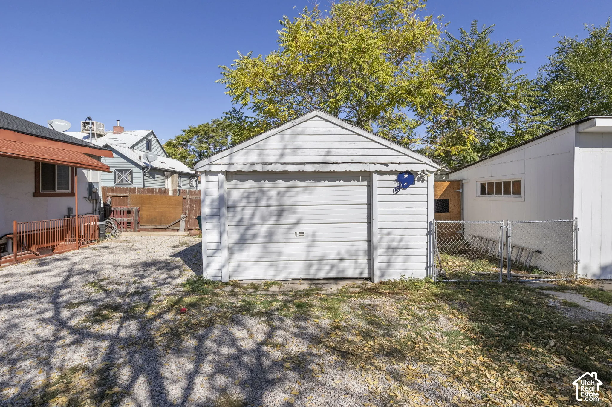 Detached garage with a roll-up door, gravel driveway, and chain-link fencing