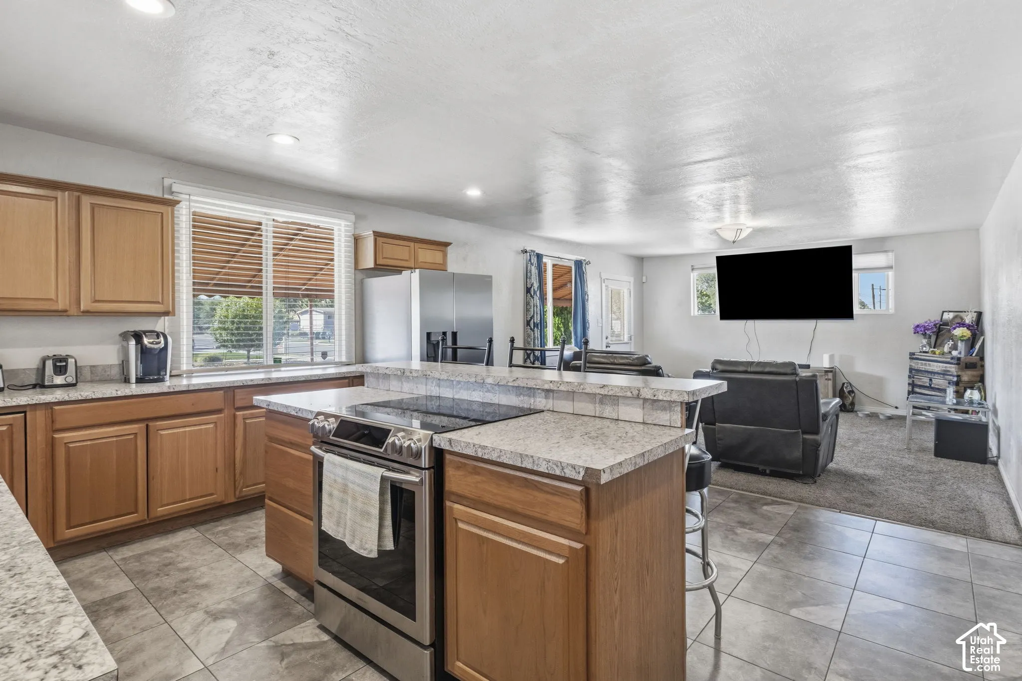 Kitchen with wood-finish cabinetry, granite-style countertops, stainless steel appliances, and tile flooring