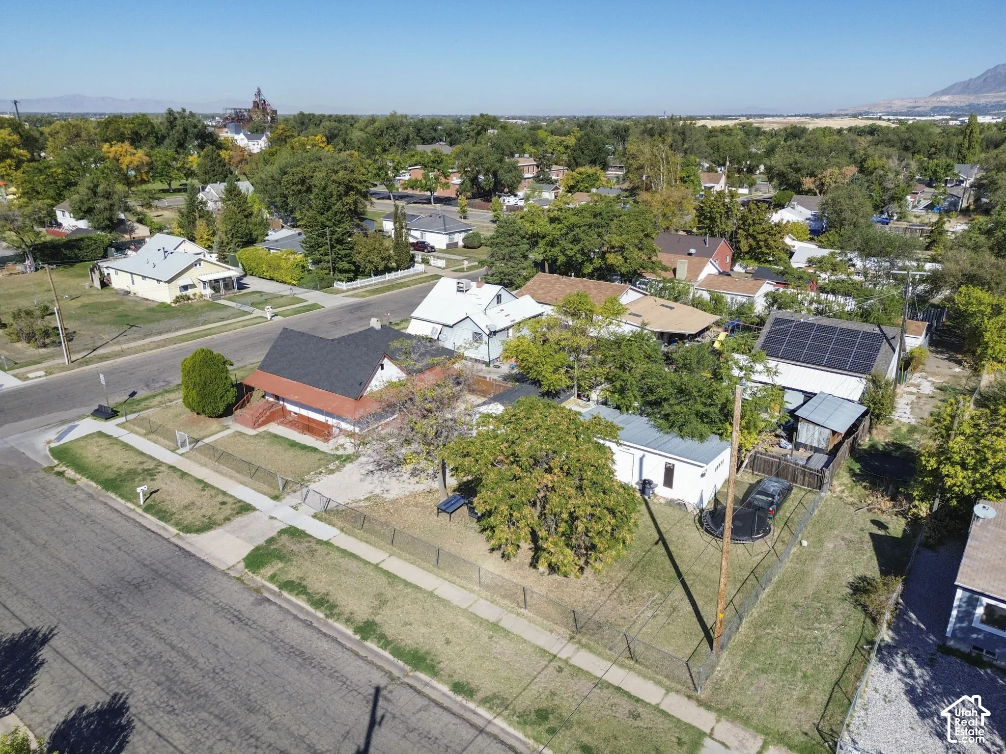 Fenced property with established trees and a paved street