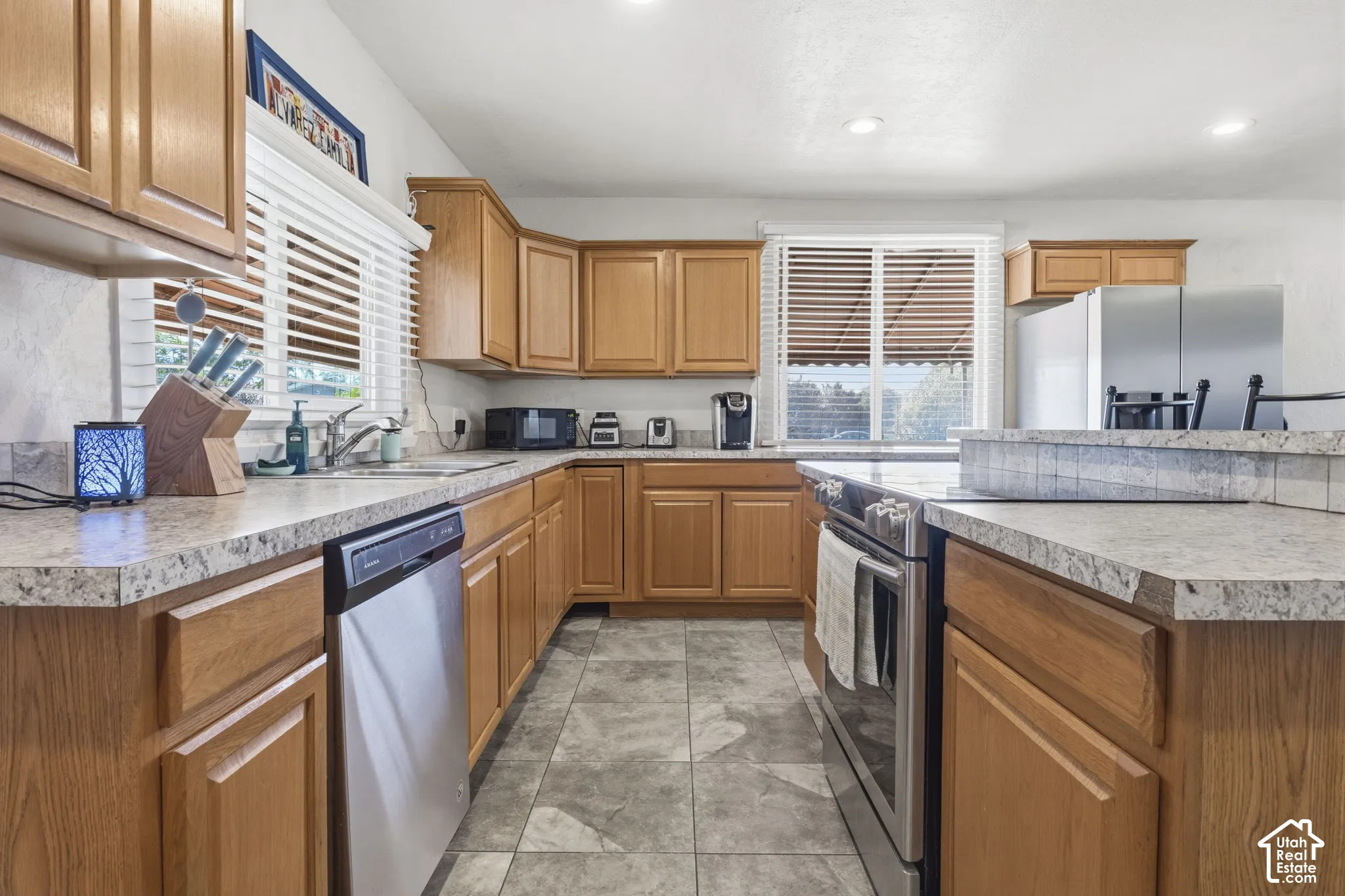 Kitchen featuring wood-finish cabinetry, stainless steel appliances, speckled countertops, and a tiled floor