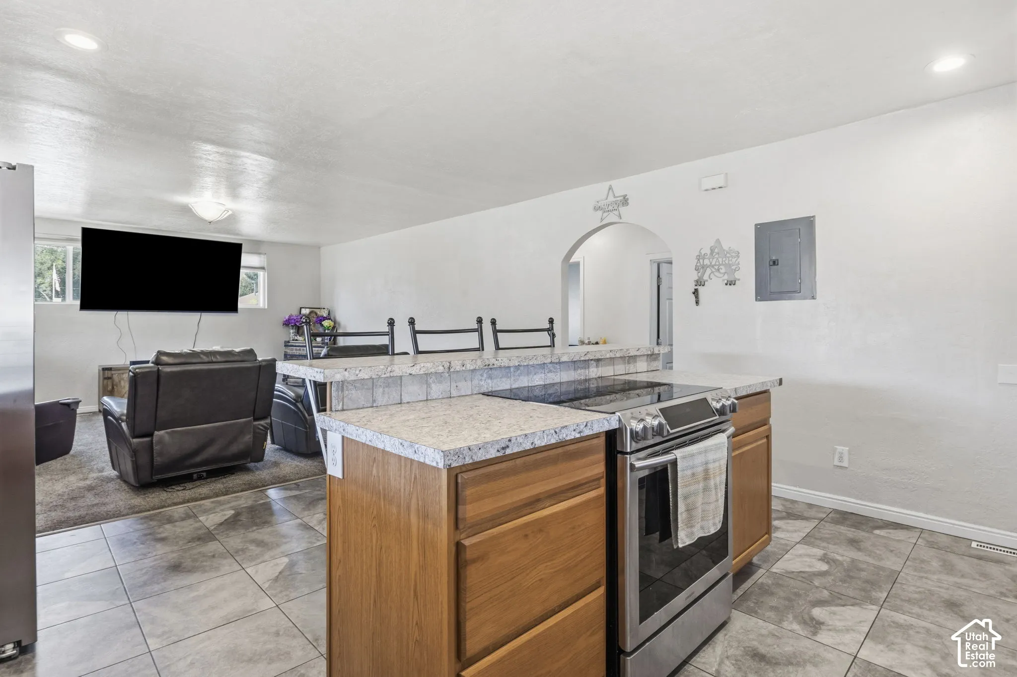 Kitchen island with a built-in stainless steel range, light wood-finish cabinetry, and a textured countertop