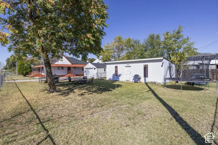 Expansive backyard with a manicured lawn, perimeter fencing, and a detached outbuilding