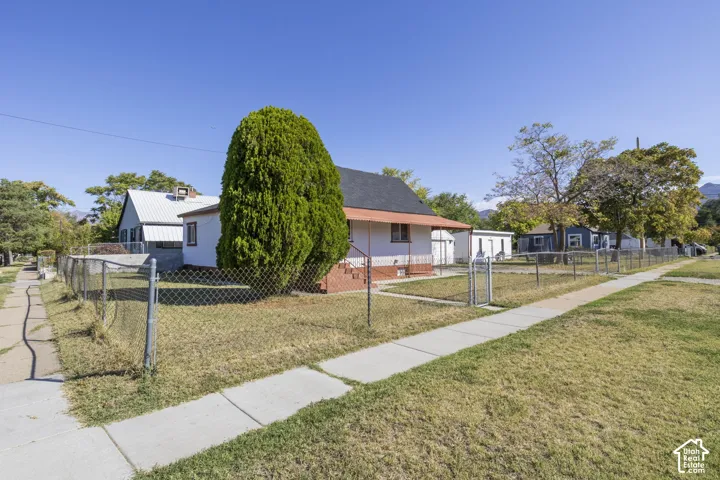 Single-story residence with a covered porch, chain-link fence, and sidewalk access