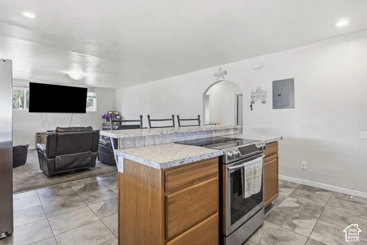 Kitchen island with a built-in stainless steel range, light wood-finish cabinetry, and a textured countertop