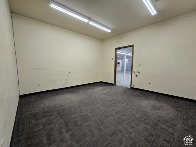 Spacious commercial or office space featuring neutral walls, overhead fluorescent lighting, and durable patterned carpet flooring throughout