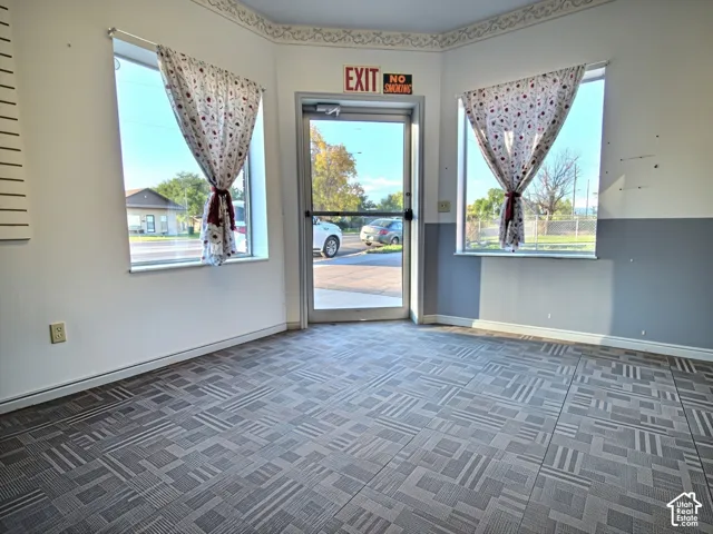Patterned carpet flooring, glass entry door, two windows with sills, two-tone wall paint, and decorative border trim