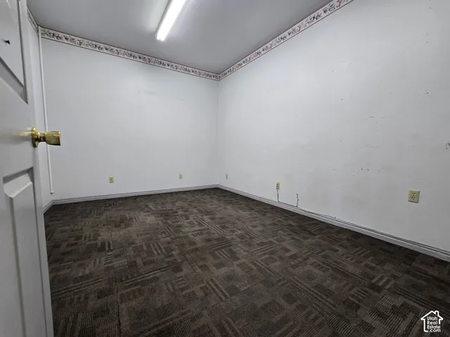 Neutral wall paint, patterned carpet flooring, and a single fluorescent light fixture