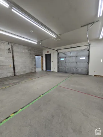 Industrial-style space featuring a roll-up door, concrete flooring, and exposed block wall