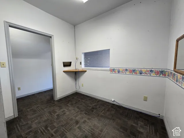 Patterned carpet flooring, built-in wooden corner shelf, and an interior window with horizontal blinds