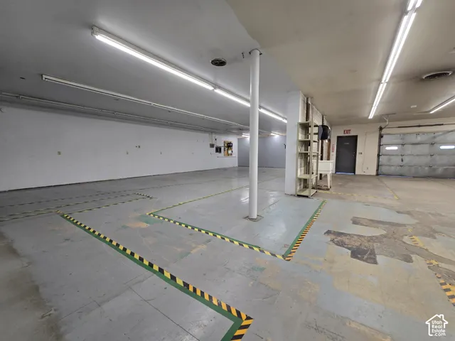 Expansive interior space with a concrete floor, exposed support column, and fluorescent strip lighting