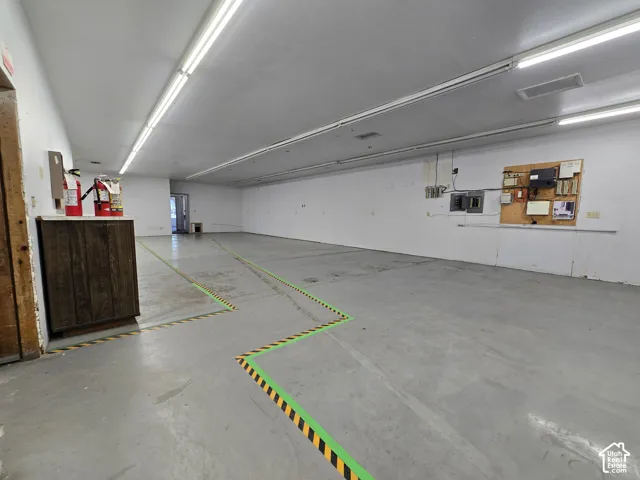 Spacious concrete flooring with white walls, illuminated by fluorescent lighting