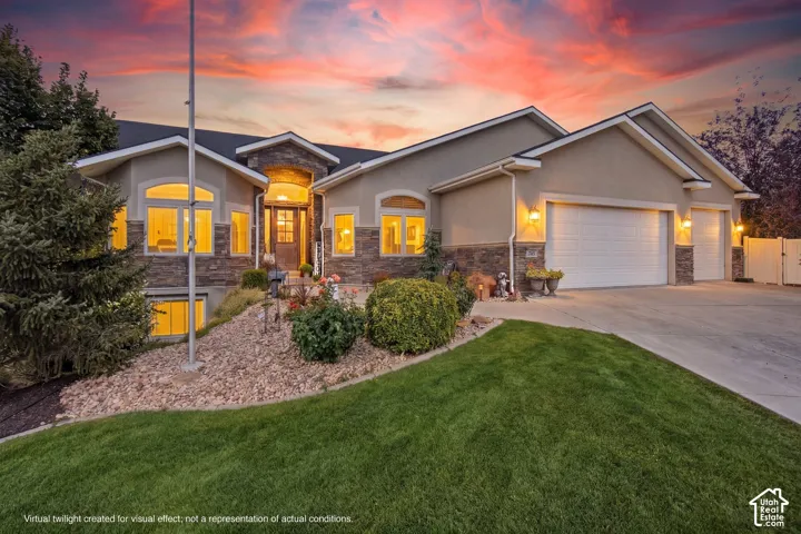 Stucco and stone exterior with arched windows, a multi-car garage, and landscaped front yard