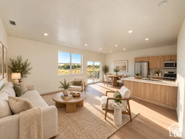 Open-concept living space with recessed lighting, wood-finish flooring, and white walls