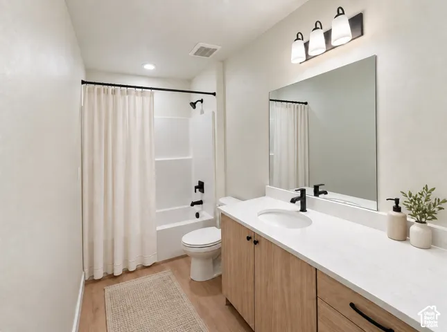 Bathroom featuring a light wood-finish vanity with a white countertop, undermount sink, and matte black faucet