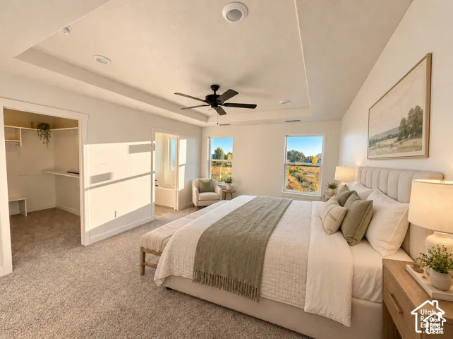 Recessed tray ceiling, neutral wall paint, ceiling fan, carpet flooring, and an organized walk-in closet-Master Bedroom