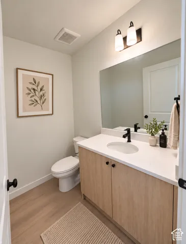 Light wood-finish vanity with a white countertop and oval undermount sink, complemented by a black single-handle faucet