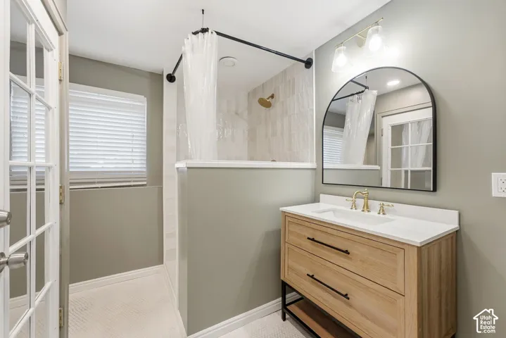 Modern vanity with white countertop, gold-finish faucet, and arched mirror