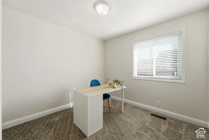Textured carpet flooring, white walls, and a single window with blinds