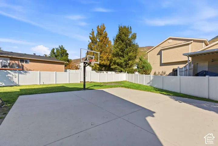 Expansive concrete pad with basketball hoop, surrounded by a white privacy fence
