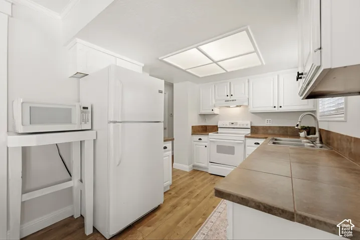 White cabinetry, wood-finish flooring, recessed ceiling lighting, and a double basin stainless steel sink