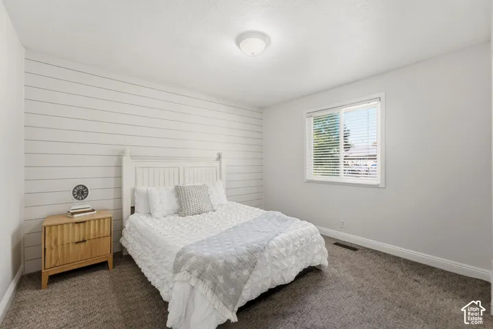 Horizontal shiplap accent wall, white-framed window with blinds, overhead flush mount lighting, and gray carpet flooring