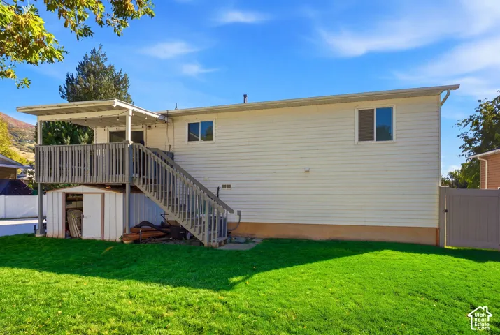 Expansive backyard featuring a manicured lawn, a two-story deck with a covered patio, and a utility shed