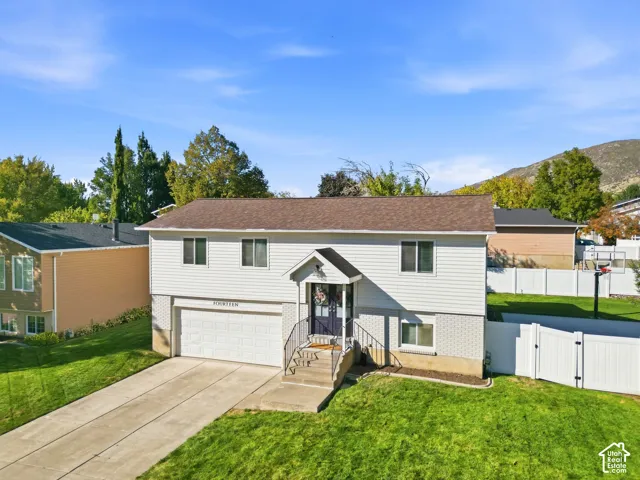 Split-level residence featuring a two-car garage, front entry with wrought iron railings, and a fenced backyard