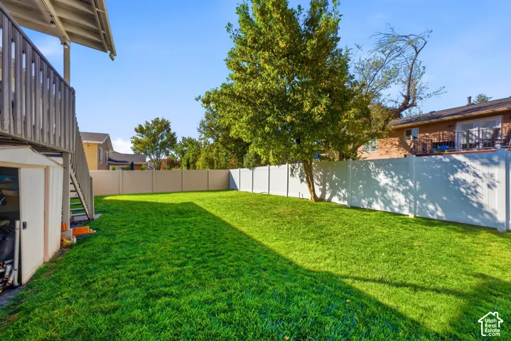 Expansive lawn area with a privacy fence, mature trees, and a storage shed
