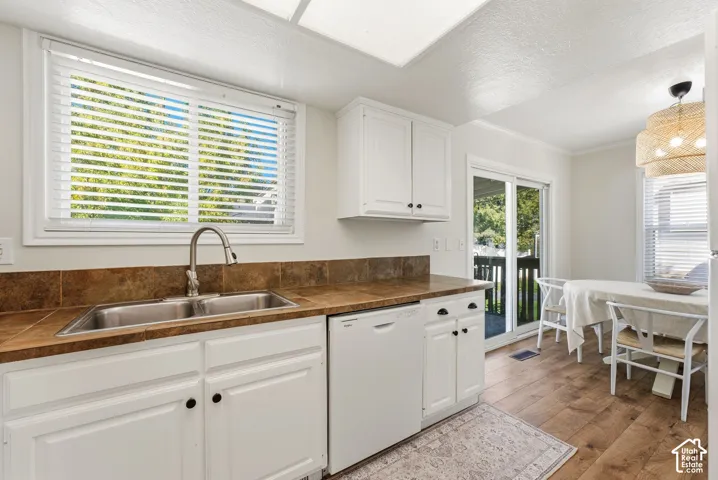 White cabinetry with black hardware, double basin stainless steel sink, and wood-finish flooring