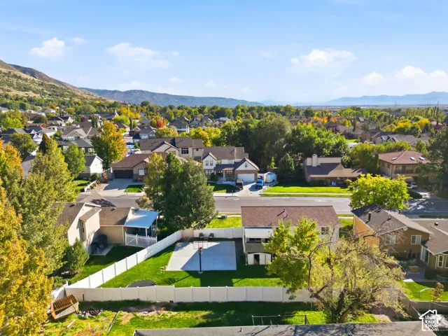 Expansive backyard featuring a green lawn, white vinyl fencing, and a built-in basketball court