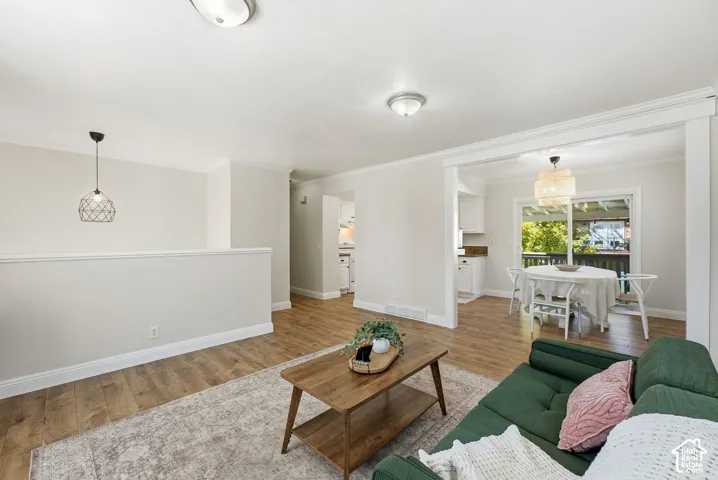 Wood-finish flooring throughout, white crown molding, and a dining area with a sliding glass door