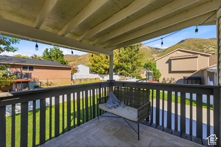 Covered patio with a painted wooden ceiling, string lighting, and dark-painted railings