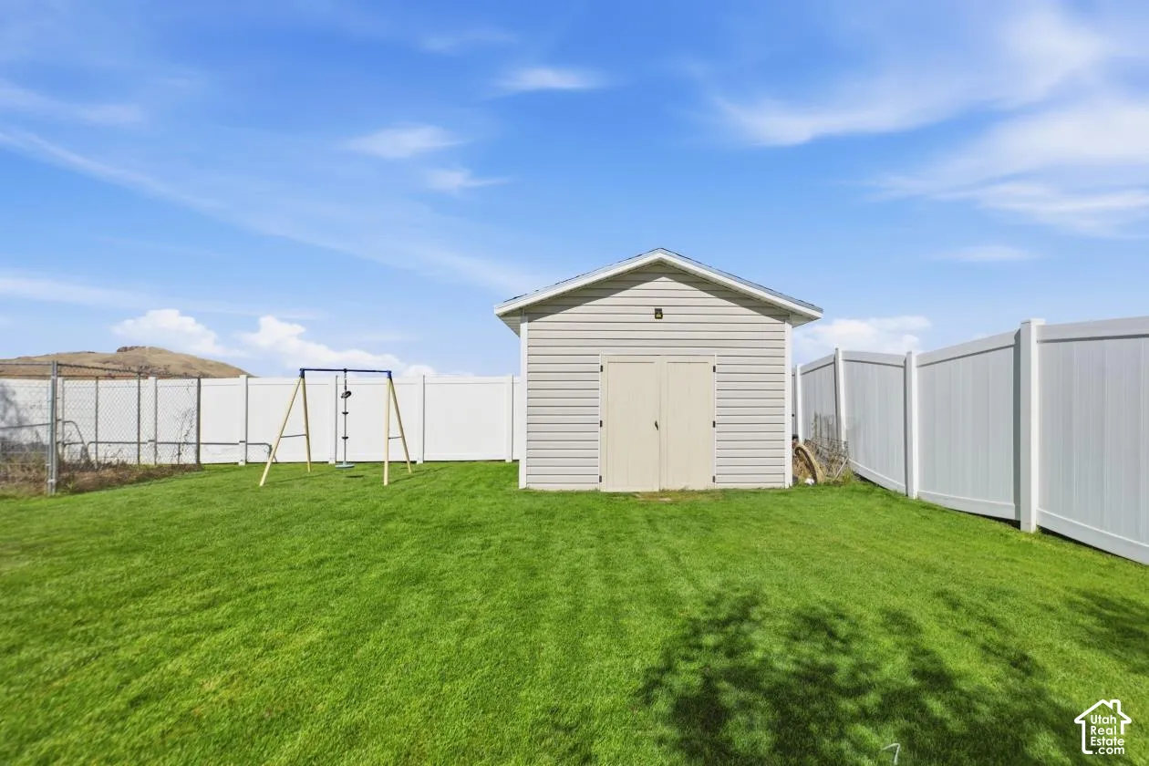 Expansive grassy yard featuring a shed with horizontal siding, double doors, and a pitched roof