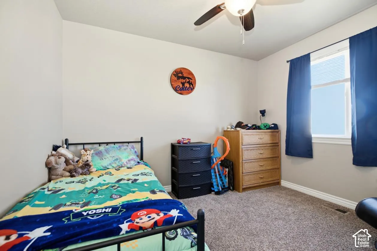 Wall-to-wall carpeting, ceiling fan with integrated lighting, and a window with blinds