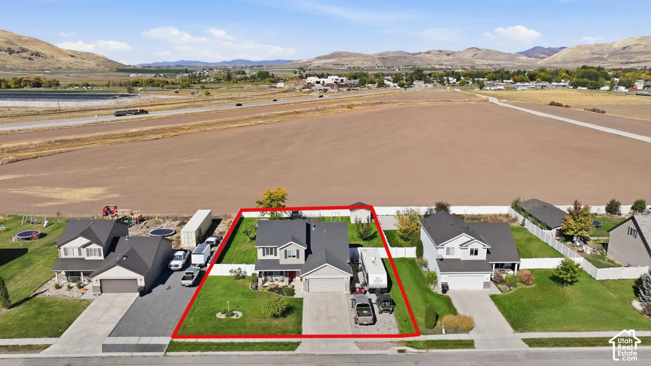 Two-story residence with an attached garage, featuring a manicured lawn and mature landscaping
