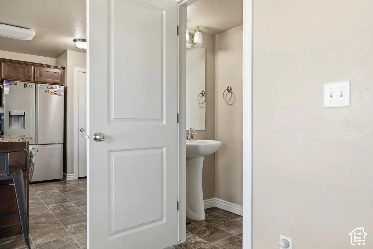 Bathroom featuring a pedestal sink, wall-mounted mirror, and wall sconce lighting
