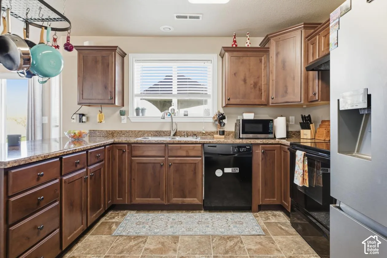 Warm wood cabinetry with ample storage throughout defines this kitchen, featuring granite countertops, stainless steel appliances, and a center island with prep space