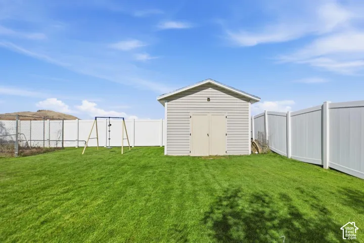 Expansive grassy yard featuring a shed with horizontal siding, double doors, and a pitched roof