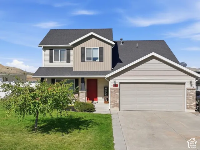 Two-story residence with a dark shingle roof, light-toned siding, and a two-car garage