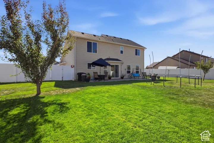 Expansive backyard featuring a manicured lawn, a concrete patio, and a privacy fence