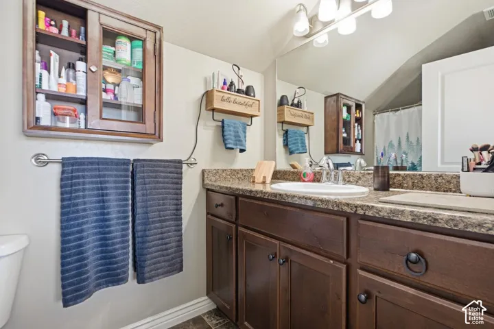 Dark wood-finish cabinetry, speckled countertop, and an integrated sink basin