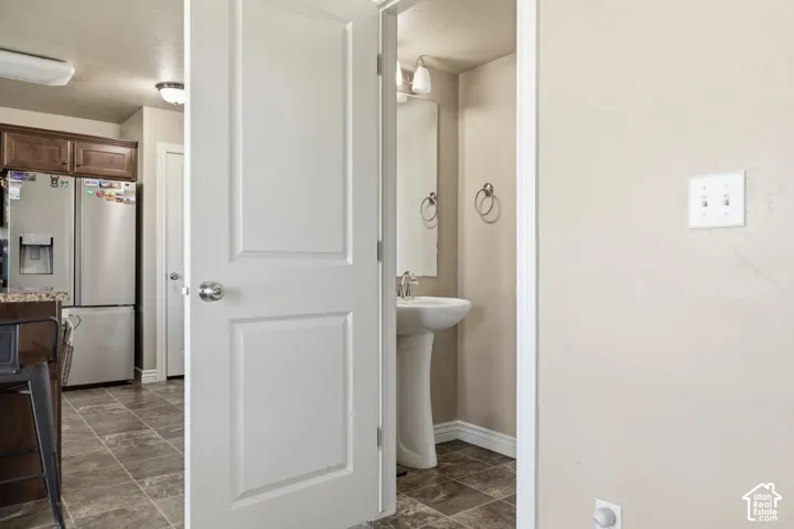 Bathroom featuring a pedestal sink, wall-mounted mirror, and wall sconce lighting
