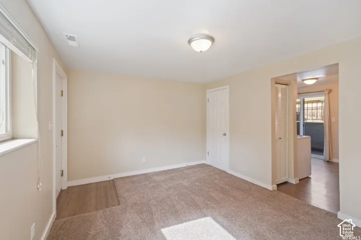Plush carpeting, recessed window, ceiling-mounted light fixture, louvered bi-fold doors, and wood-finish flooring