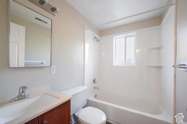 Bathroom featuring a white bathtub, shower with built-in shelving, wood-finish vanity with an integrated sink, and a framed mirror with overhead lighting
