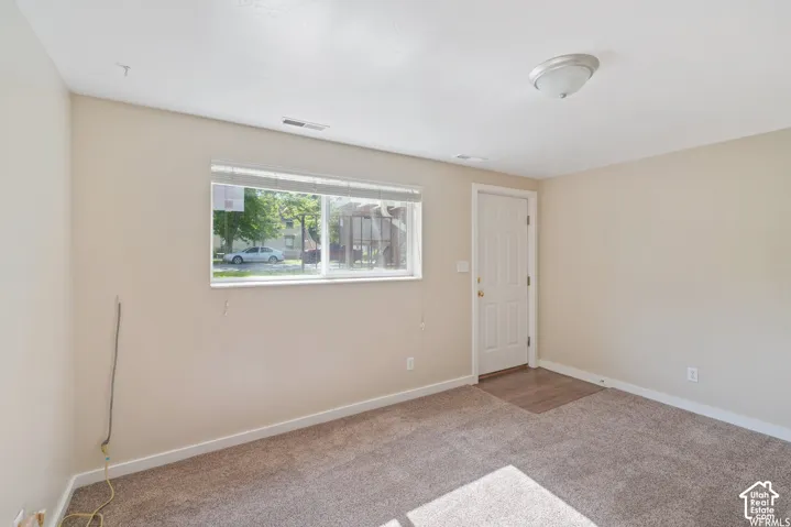 Neutral wall color, carpet flooring, window with blinds, overhead flush-mount light fixture, and white door with dark hardware