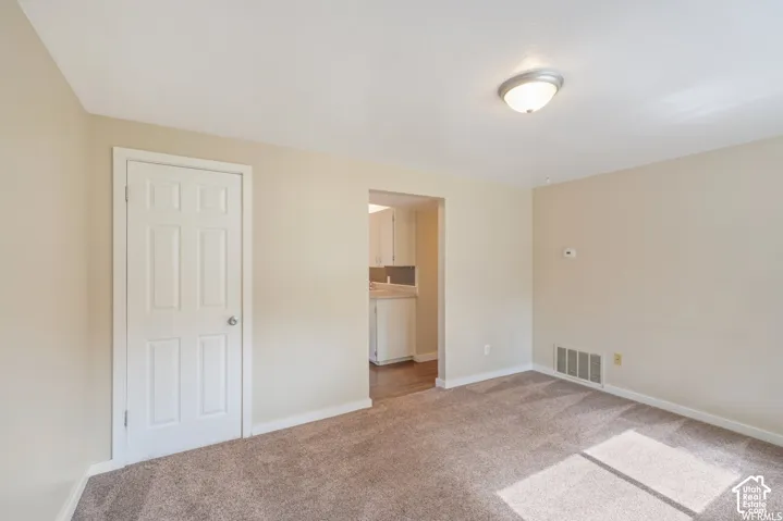 Wall-to-wall carpeting in a neutral tone, ceiling-mounted light fixture, and a paneled interior door
