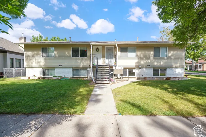 Duplex property featuring a concrete walkway, two separate entrances, and a manicured lawn