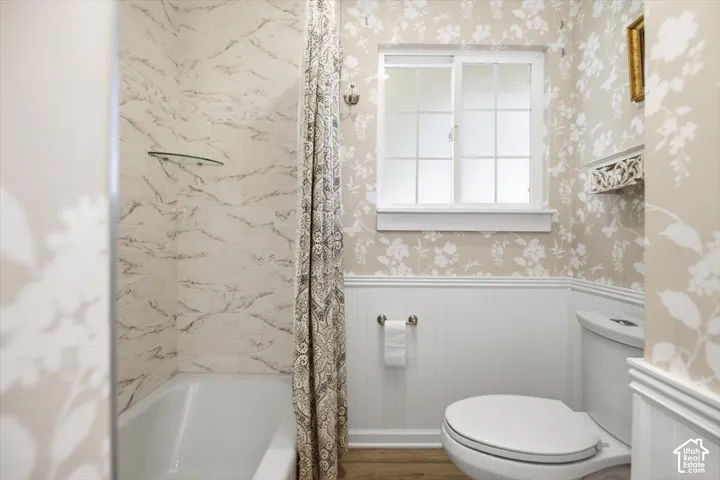 Bathtub with marble-look tile surround and glass shelf