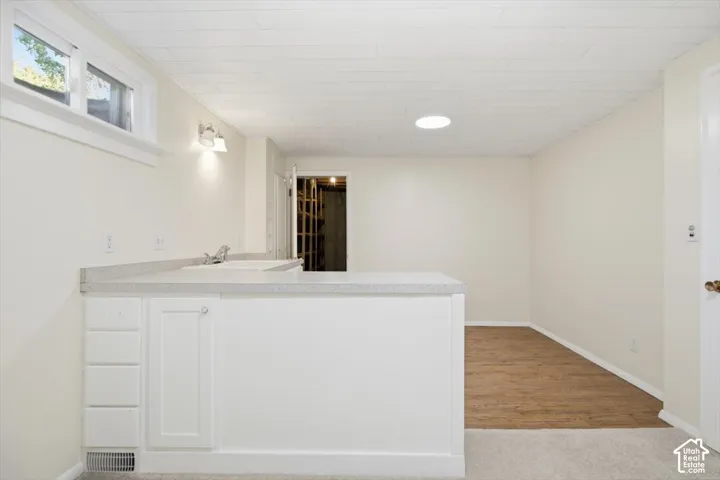 Wet bar with white cabinetry, light-toned countertop, and undermount sink