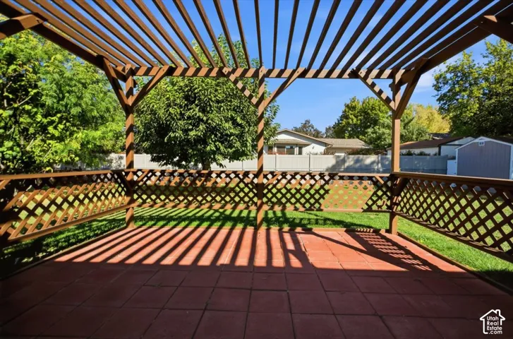 Expansive patio featuring a wood pergola and red tile flooring